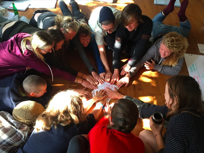 A group of activists in a circle placing their hands on a piece of paper to make a decision.